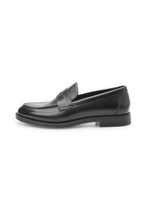 Mocasines de cuero negro con un acabado suave, punta redondeada y una correa decorativa en la parte frontal. Suela de goma plana, diseño clásico.