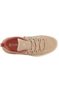 Sneaker in camoscio beige con lacci grigi, linguetta testurizzata e interno rosso. Presenta il logo e perforazioni sulla punta. Stile classico da campo.