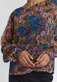 Blusa floreale con vestibilità ampia, realizzata in tessuto leggero. Presenta un motivo multicolore, maniche lunghe e un orlo dritto.