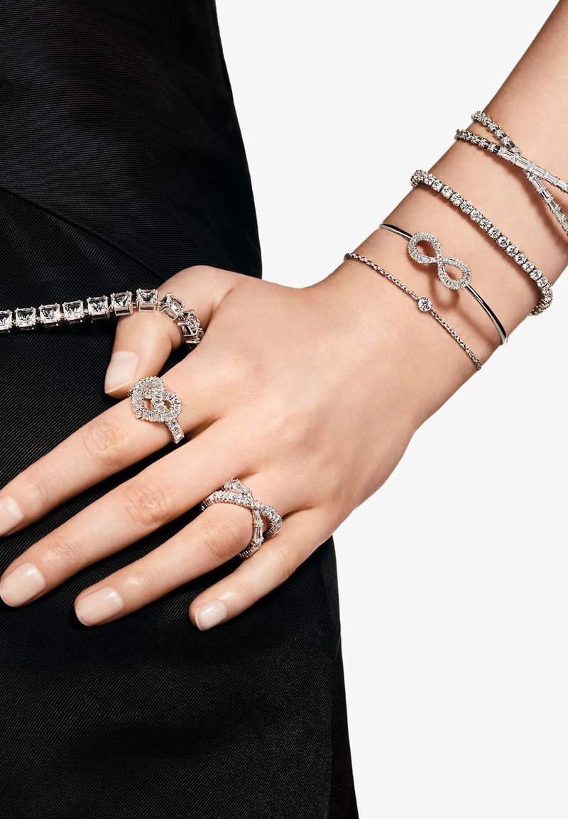 Joyería de plata con piedras de zirconia cúbica transparentes, que incluye pulseras y varios anillos, entre ellos diseños de infinito y de corazón.