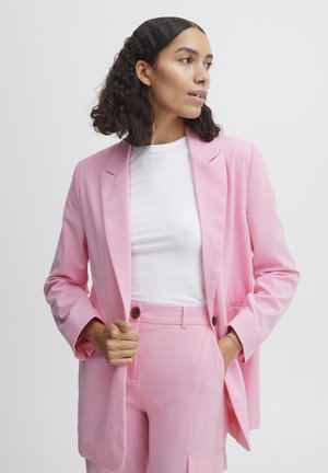 Pink tailored blazer with notch lapels, long sleeves, and a relaxed fit, paired with a white fitted T-shirt and matching pink trousers.