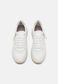 Sneakers bianchi con una tomaia in pelle liscia, dettagli perforati, una cerniera su un lato e un accento beige sul tallone.
