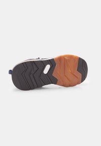 Suola della scarpa con una base in gomma nera e un motivo a zigzag. Presenta un accento in gomma arancione nel tallone e una piccola linguetta.