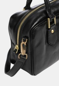 Borsa a tracolla nera in pelle con un design strutturato, chiusura con zip dorata e tracolla removibile. Presenta dettagli in ottone e cuciture a vista.