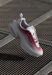 Tenisky Nike Air Max s gradientným dizajnom v bielej a ružovej farbe, hladkým povrchom, zaoblenou špičkou a výraznými logami.