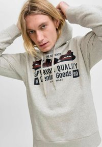 Světle šedá mikina s kapucí a přední kapsou, která je zdobena černým a červeným grafickým potiskem s nápisem "Superior Quality Denim Goods." Měkký textilní povrch.