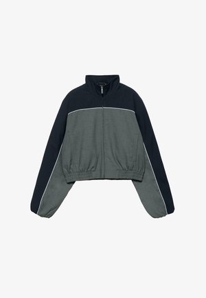 Krótka kurtka z wysokim kołnierzem, z przodu zamek błyskawiczny, elastyczny pas, w kolorach blokowych: ciemny granat i szary, z białą lamówką na rękawach i na klatce piersiowej.