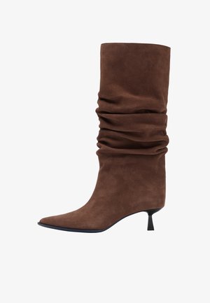 Smeđa kožna čizma od brušene kože, opuštenog dizajna, šiljasti vrh, kratka blok peta, glatka tekstura, sa presavijenim tkaninskim detaljima oko vrata čizme.