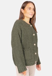 Olivengrüner, strukturierter Strick-Cardigan mit rundem Halsausschnitt, der auffällig mit fünf dekorativen Knöpfen und zwei Fronttaschen ausgestattet ist.