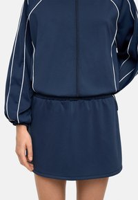 Granatowa, długosleeve'owa sportowa sukienka z białymi lamówkami, z zapięciem na zamek, elastycznym paskiem w talii i gładką fakturą materiału.