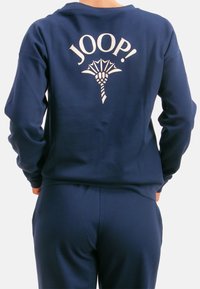Granatowa bluza z dużym białym logo "JOOP!" i grafiką na plecach, z długimi rękawami i luźnym krojem.
