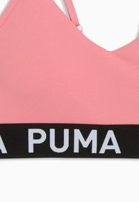 Ροζ αθλητικό σουτιέν με μαύρη ελαστική ταινία που φέρει λευκό κείμενο "PUMA", με μινιμαλιστικό σχεδιασμό και ρυθμιζόμενους ιμάντες ώμων.