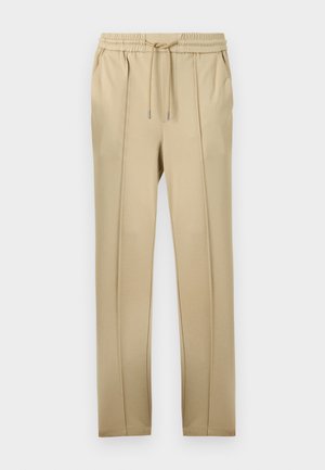 Beige joggebukser med elastisk midjebånd og justerbar snøring. Har to sidelommer og et glatt, lett stoff.