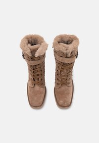 Bottines en suède marron à lacets avec doublure en fausse fourrure, présentant un bout rond et une semelle en caoutchouc. Sangle ajustable en accent en haut.