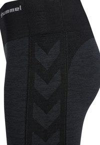 Leggings sportivi neri con una texture a coste, caratterizzati da un motivo a chevron lungo il lato e una vita larga ed elastica con logo.