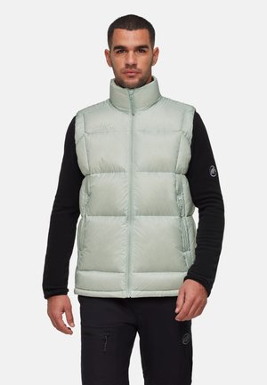 Licht mintgroene puffer vest met hoge kraag, ritssluiting en horizontaal quiltpatroon, gedragen over een zwart langemouwen shirt.
