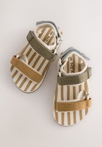 Sandales pour enfants avec une base blanche et des brides rayées en beige, vert et bleu. Fermetures en velcro ; bout rond avec une semelle texturée.