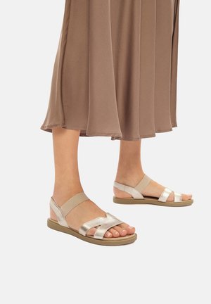 Sandale metalice argintii cu multiple curele într-un design încrucișat, dotate cu o talpă cu amortizare și o construcție minimalistică.