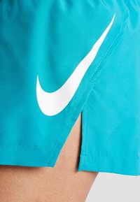 Turkusowe spodenki sportowe z białym logo Nike. Posiadają boczny rozcięcie dla większej swobody ruchów oraz gładką, lekką tkaninę.