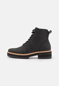 Cizmă ankle neagră, realizată din piele netedă, cu vârf rotund, design cu șireturi, curea de prindere și talpă groasă din cauciuc cu textură.