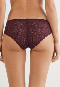 Bordeaux kant hipster onderbroek met geschulpte randen, voorzien van een bloemenpatroon en verfijnde details. Zachte, delicate textuur.