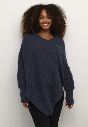 Navy knitted poncho with zigzag patterns, V-neck, and long sleeves. Fabric has a soft texture with openwork detailing, creating a layered look.