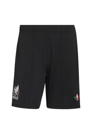 Homme portant un short de football noir du Mexique, des chaussettes noires assorties avec des rayures vertes, blanches et rouges, des crampons, tenant un ballon de football multicolore.