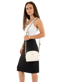 Borsa bianca trapuntata con catena argentata e logo triangolare. Texture liscia, forma arrotondata e chiusura con cerniera dal design elegante.