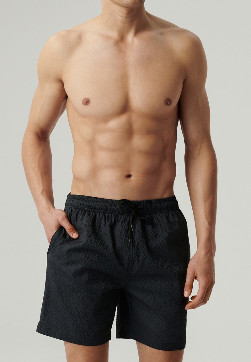 Czarne szorty kąpielowe z teksturowanej tkaniny, z elastycznym pasem i sznurkiem do regulacji. Posiadają boczne kieszenie i luźny krój.