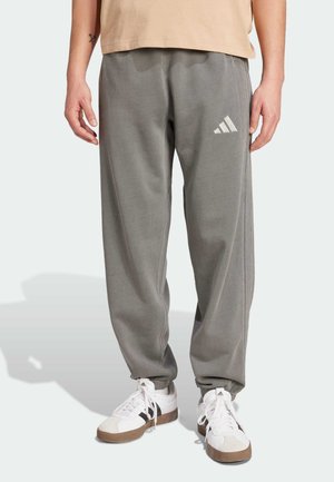 Pantalons de survêtement gris avec taille élastique, arborant un logo Adidas blanc. Fabriqués en matériau doux avec une coupe décontractée et des poignets côtelés.