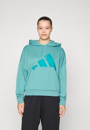 Turkizna kapuca majica z velikim teal logotipom na sprednji strani, z kengurujskim žepom in sproščenim krojem. Mehak material, dolgi rokavi.