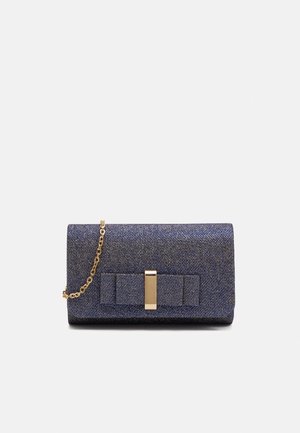 Marineblauwe glitter clutch met decoratieve strik en gouden rechthoekige sluiting, voorzien van een korte gouden kettingriem op een lichte achtergrond.