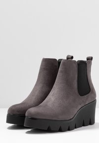 Bottines en suédine grise avec une semelle en wedge, des panneaux latéraux élastiques et des tirants à l'arrière ; finition texturée et motif de semelle géométrique.