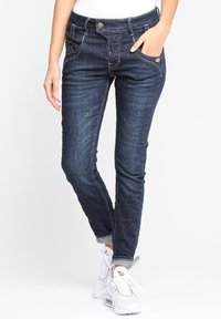 Smala mörkblå jeans med en slät textur, fem fickor och lätt blekning. Har en knappstängning och sydda detaljer.