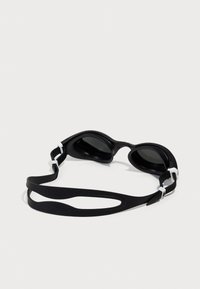 Black swimming goggles with a soft silicone frame, tinted lenses, and a flexible strap featuring white accents. Streamlined design for comfort.