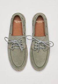 Chaussures en suède gris avec une texture lisse, présentant un bout arrondi, un laçage à l'avant et un intérieur en cuir tan. Détails piqués le long des bords.