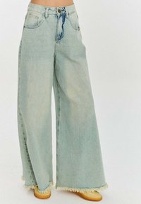 Světle modré džíny širokého střihu vyrobené z denimu, se zkoseným lemem, pěti kapsami a zapínáním na knoflík a zip v pase.