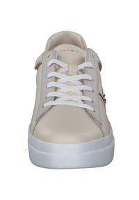 Beżowe sneakersy z gładkiego syntetycznego materiału, z białymi sznurówkami i białą gumową podeszwą. Zawierają subtelną markę na bocznej części.