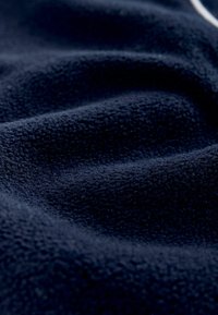 Tumesinine fliisriie, millel on tekstuuriga pind, pehmed voldid ja õrn, kergelt reljeefne muster.