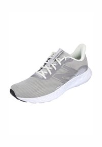 Zapatilla deportiva gris con parte superior de malla, suela media blanca y suela exterior negra. Cuenta con cordones y un logo decorativo en el costado.