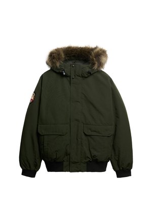 Giacca verde isolata con cappuccio bordato di pelliccia, due tasche frontali e polsini elasticizzati. Presenta una chiusura centrale con zip e bottoni.