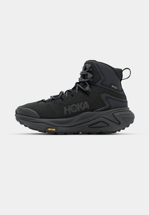 Sorte vandreture støvler med høj ankel og struktureret overdel, der har snørelukning, gummisål og Vibram-branding. Vandtæt GORE-TEX materiale.
