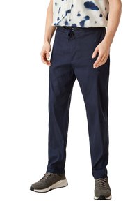 Mörkblå linnebyxor med avslappnad passform, dragsko i midjan och sidofickor, i kombination med grå sportskor.