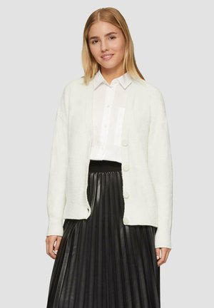 Witte, fluffy cardigan met een losse pasvorm, lange mouwen en vijf knopen aan de voorkant, gedragen over een zwarte, geplisseerde midi-jurk.