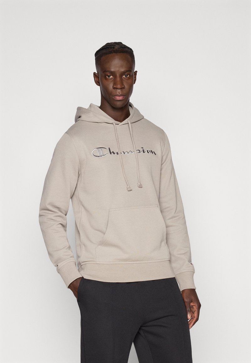 Μπεζ φούτερ με κουκούλα, μπροστινή τσέπη και κορδόνι, με ασημένιο κεντημένο λογότυπο "Champion" στο στήθος.