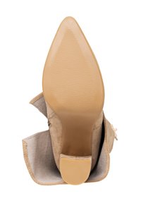 Beige mockaskinn högklackad stövel med spetsig tå och texturerad gummi-sula. Har sydd dekoration och en vikt tygkant längst upp.