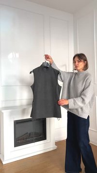 Top gri fără mâneci, cu guler fals, expus pe un umeraș; prezintă o siluetă ajustată, material moale și găuri laterale subtile pentru un plus de detaliu.