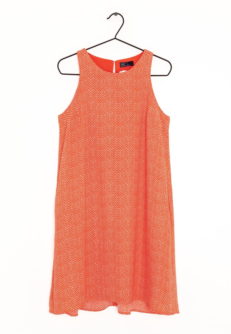 Robe rouge avec un motif en chevron, sans manches, encolure ronde et fermeture éclair au dos. Tissu léger et forme légèrement évasée.