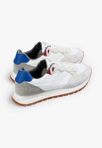 Weiße und graue Sneakers mit einem Mesh-Obermaterial, Suede-Akzenten, roten und blauen Details sowie einer Gummisohle mit Rillen für besseren Halt.