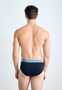 Marineblauwe aansluitende boxershort met een lichtgrijze elastieken tailleband; gladde textuur, minimalistisch ontwerp, met een lage beenopening en een strakke pasvorm.